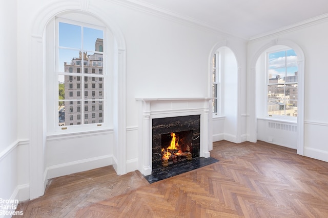 unfurnished living room featuring radiator heating unit, parquet floors, crown molding, and a premium fireplace