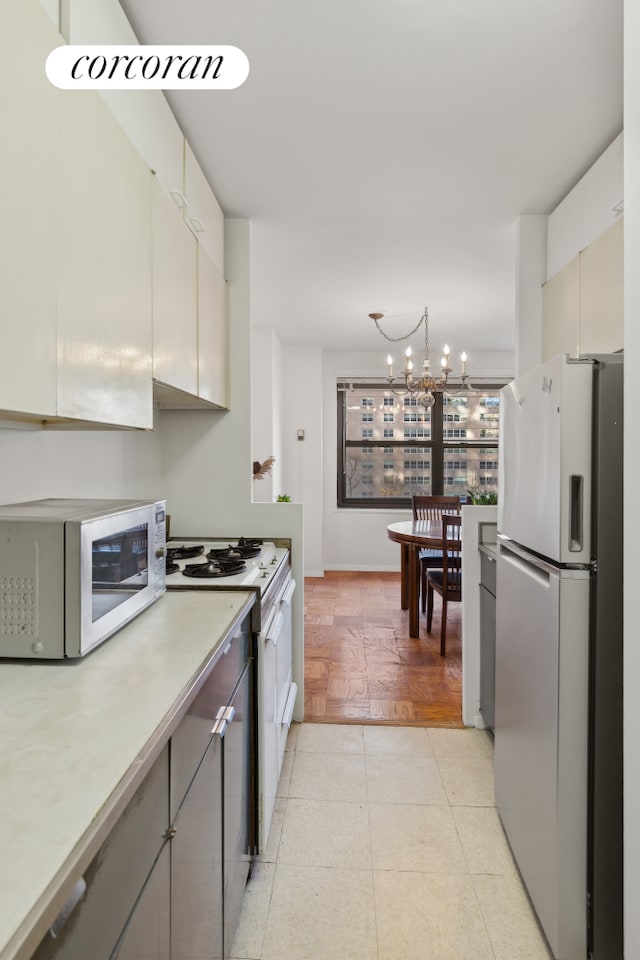 kitchen featuring light tile patterned flooring, white appliances, and an inviting chandelier