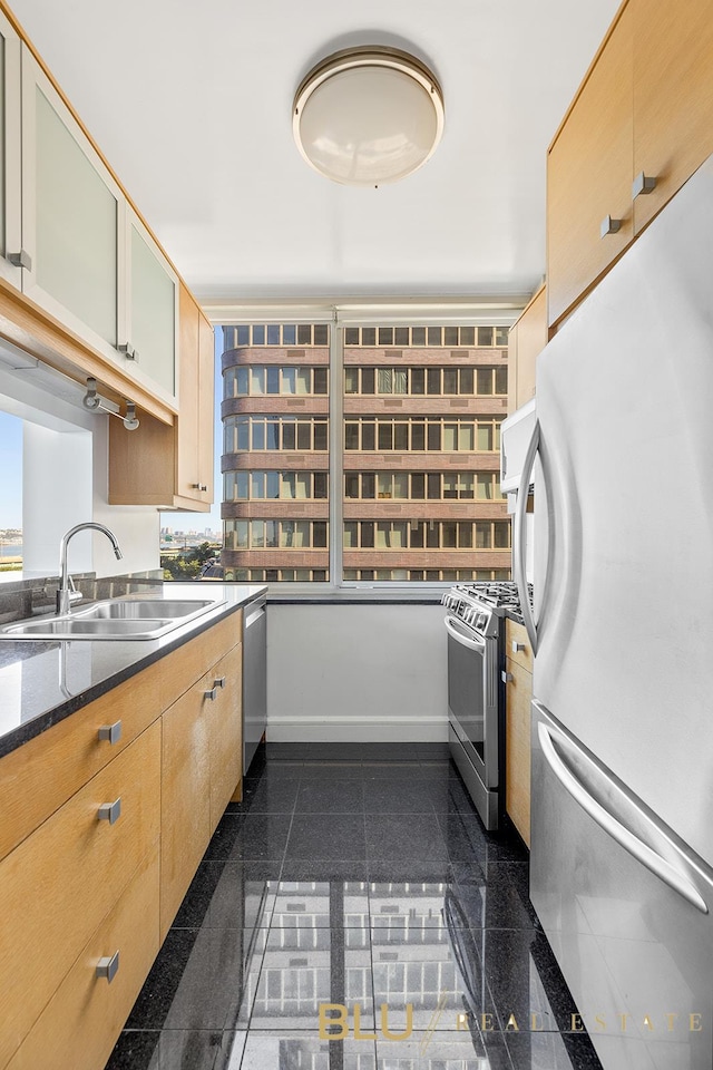 kitchen featuring dark stone countertops, sink, light brown cabinets, and appliances with stainless steel finishes