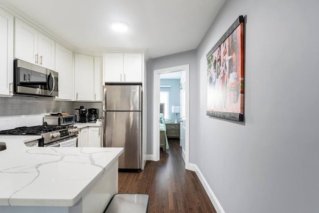 kitchen featuring light stone countertops, white cabinetry, kitchen peninsula, and appliances with stainless steel finishes