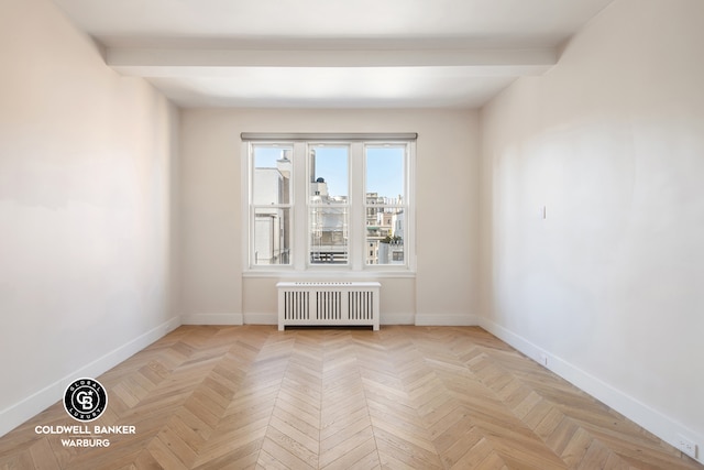 spare room with beam ceiling, radiator, and light parquet floors