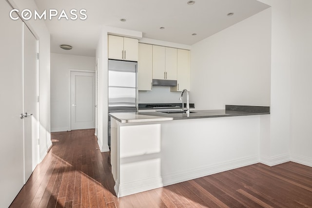 kitchen with kitchen peninsula, dark hardwood / wood-style floors, high end fridge, and sink