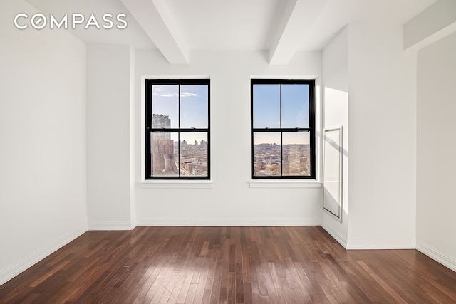 spare room with beamed ceiling and dark hardwood / wood-style flooring