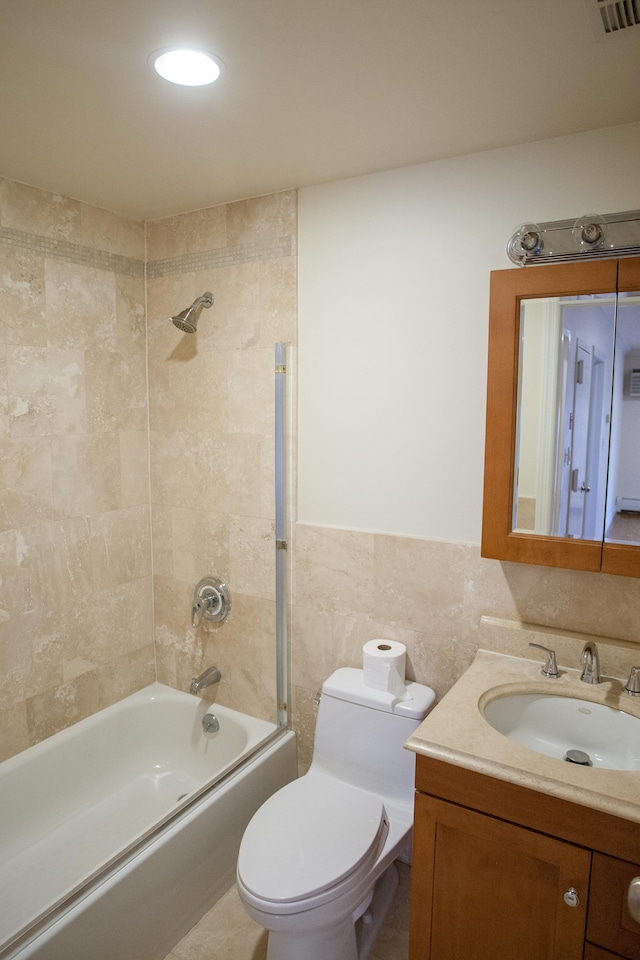 full bathroom featuring tiled shower / bath combo, toilet, tile walls, and vanity