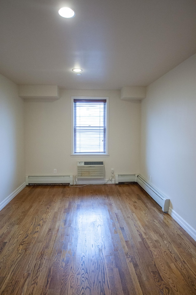 empty room with hardwood / wood-style floors, a wall unit AC, and a baseboard heating unit