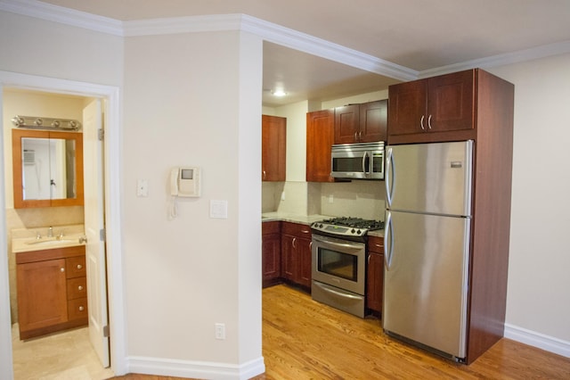 kitchen with backsplash, stainless steel appliances, crown molding, sink, and light hardwood / wood-style flooring