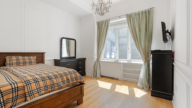 bedroom featuring crown molding, a chandelier, and light wood-type flooring