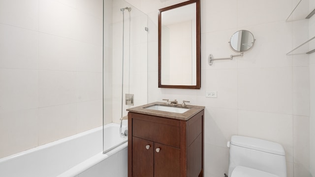 full bathroom with tiled shower / bath, vanity, tile walls, and toilet