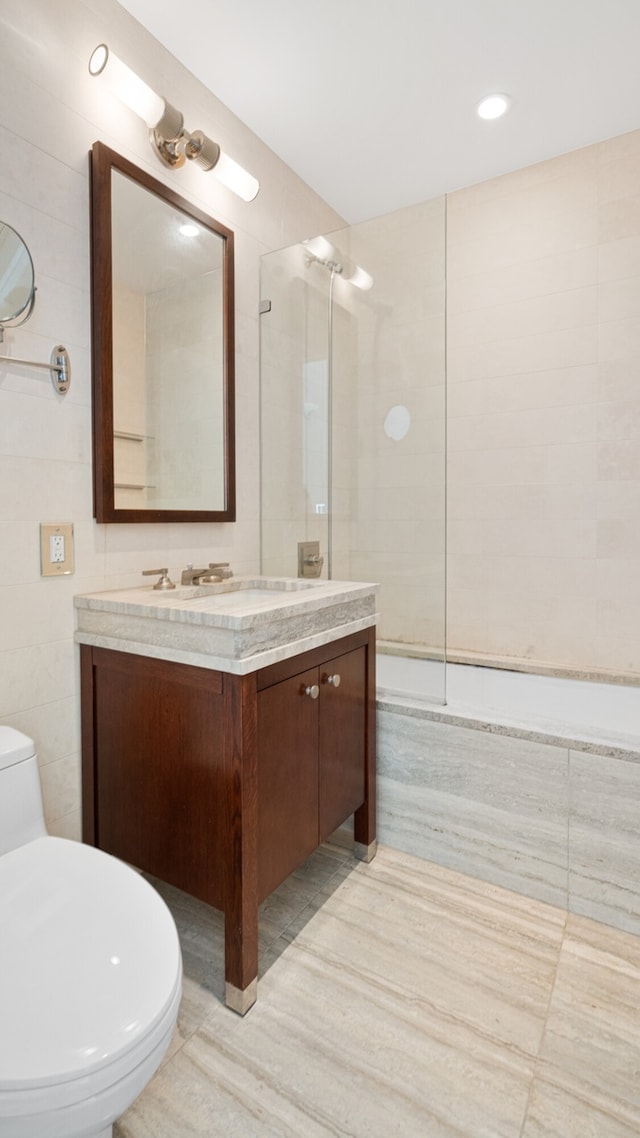 full bathroom featuring tile walls, vanity, tiled shower / bath combo, and toilet