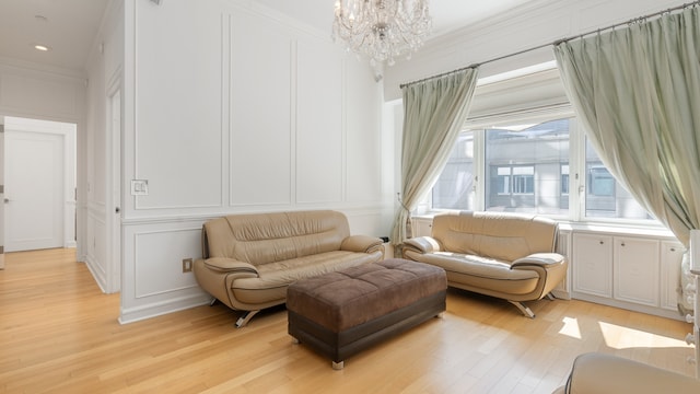 sitting room with light wood-type flooring, crown molding, and an inviting chandelier