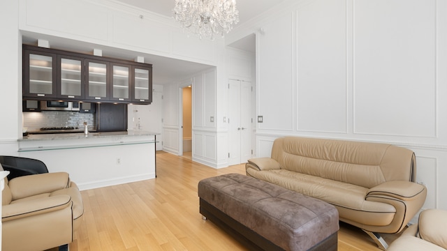 living room featuring crown molding, light hardwood / wood-style floors, and a notable chandelier