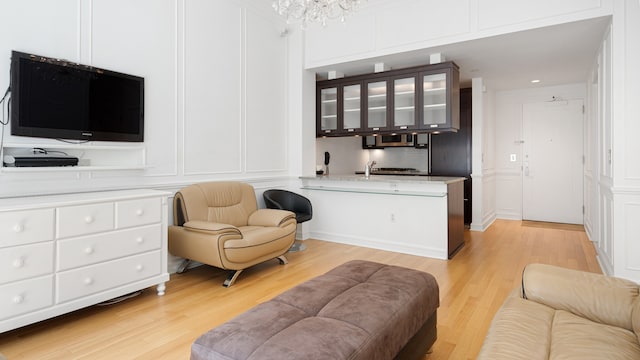 living room featuring light wood-type flooring, a notable chandelier, and sink