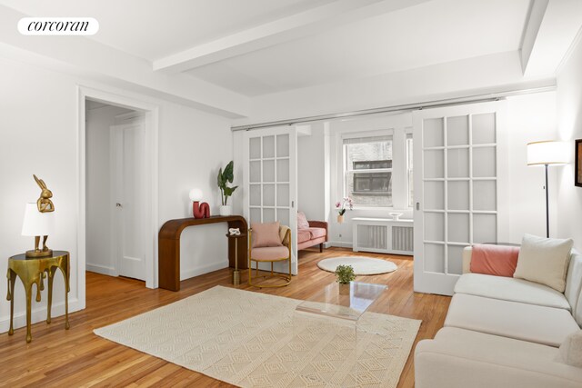 living room with radiator heating unit, beam ceiling, and wood-type flooring