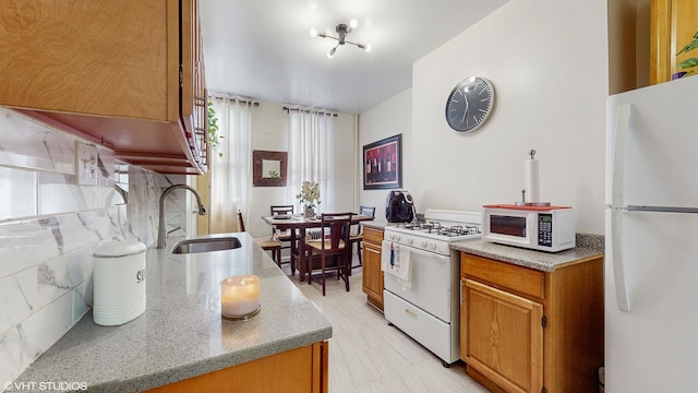 kitchen featuring white appliances, backsplash, a notable chandelier, and sink