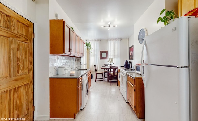 kitchen with tasteful backsplash, white appliances, sink, a notable chandelier, and washer / clothes dryer