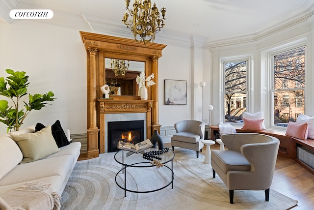 living room featuring a notable chandelier, ornamental molding, and light hardwood / wood-style flooring