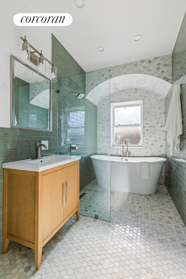 bathroom featuring decorative backsplash, plus walk in shower, vanity, and tile walls