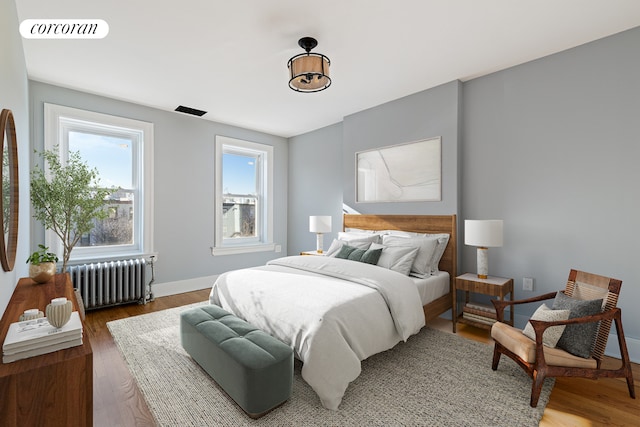 bedroom with dark hardwood / wood-style floors and radiator