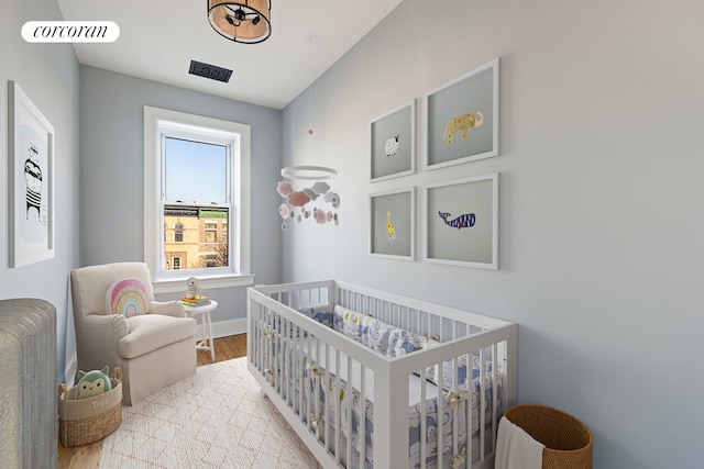 bedroom with light hardwood / wood-style flooring and a nursery area