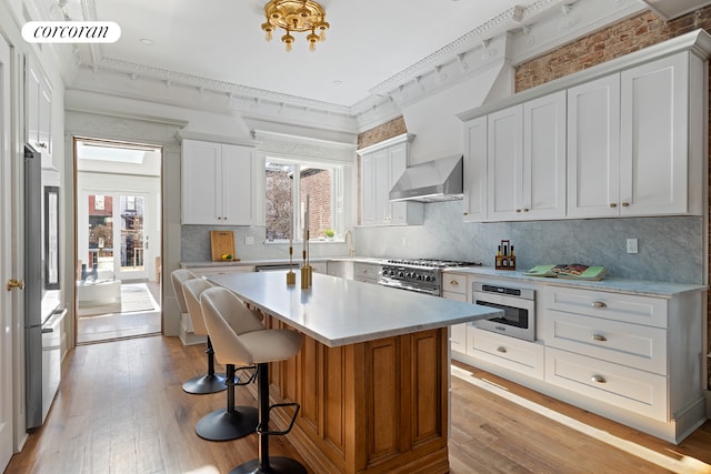 kitchen featuring white cabinetry and wall chimney range hood