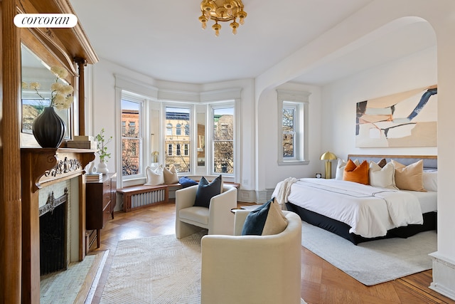 bedroom with radiator heating unit, multiple windows, and light parquet flooring