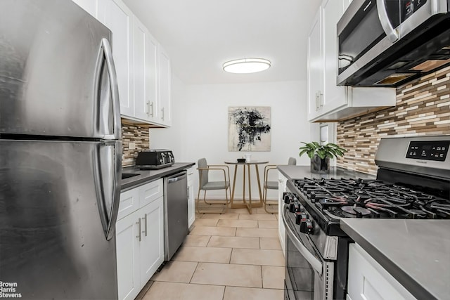 kitchen with light tile patterned floors, white cabinetry, backsplash, and appliances with stainless steel finishes