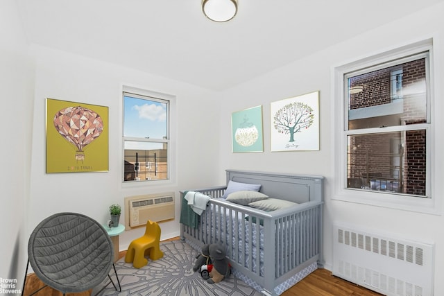 bedroom with a wall unit AC, radiator, and a nursery area