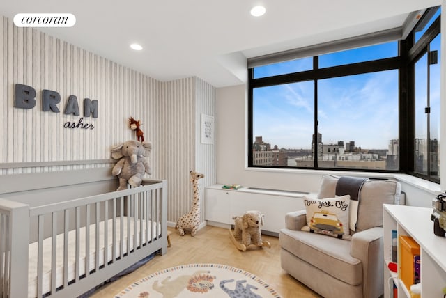 bedroom with light parquet flooring and a crib