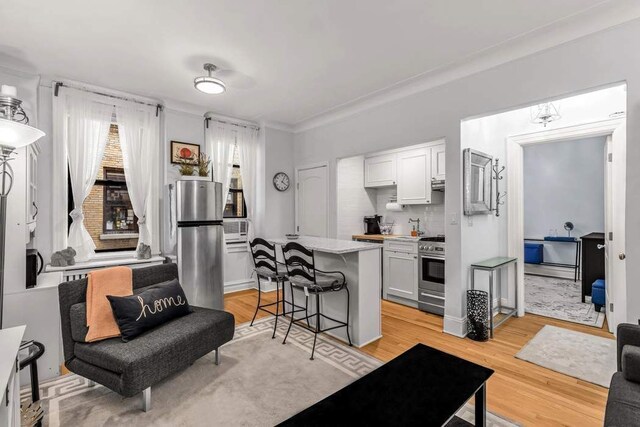 kitchen featuring a kitchen breakfast bar, white cabinetry, light hardwood / wood-style floors, and appliances with stainless steel finishes