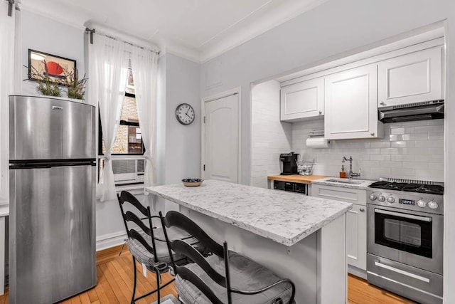 kitchen featuring appliances with stainless steel finishes, white cabinetry, a kitchen breakfast bar, and sink