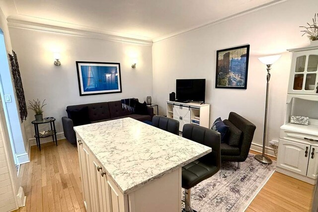 bedroom featuring light hardwood / wood-style floors, radiator heating unit, ornamental molding, and an inviting chandelier