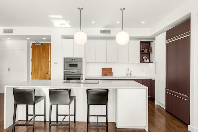 kitchen with stainless steel double oven, black electric cooktop, sink, white cabinets, and a kitchen island