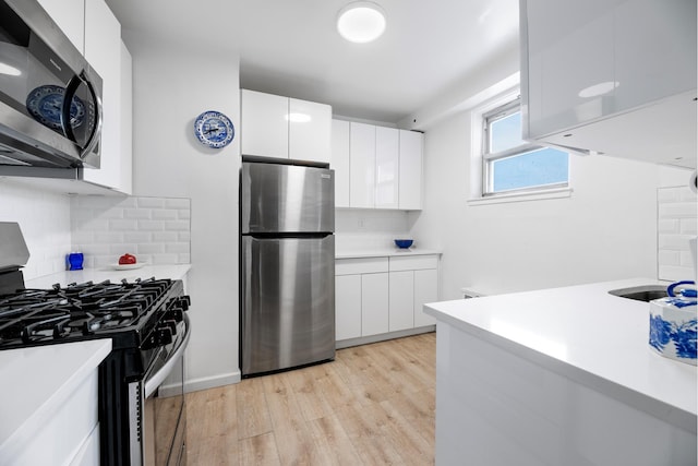 kitchen with white cabinets, backsplash, stainless steel appliances, and light hardwood / wood-style floors