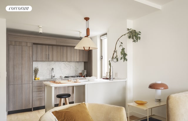 kitchen with kitchen peninsula, tasteful backsplash, a breakfast bar, sink, and decorative light fixtures