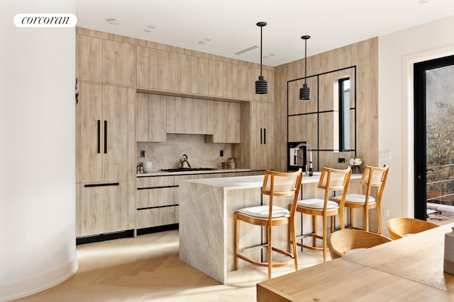 bar with light brown cabinets, light parquet flooring, hanging light fixtures, and sink