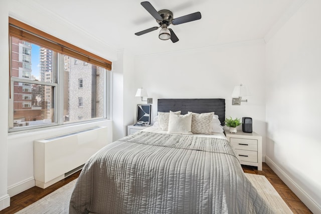 bedroom featuring multiple windows, ceiling fan, wood-type flooring, and ornamental molding