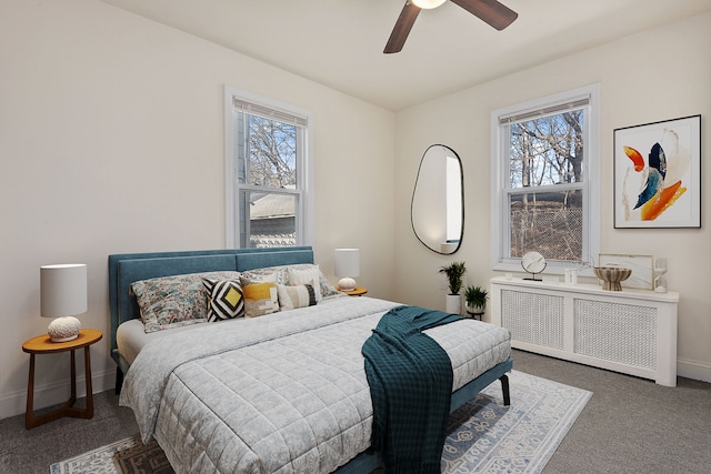 carpeted bedroom with ceiling fan, radiator, and multiple windows