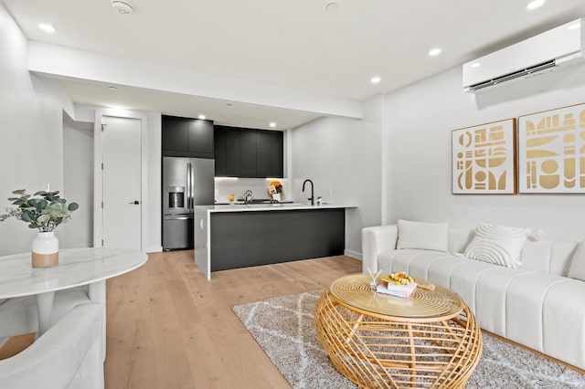 living room with light hardwood / wood-style floors, sink, and a wall mounted AC