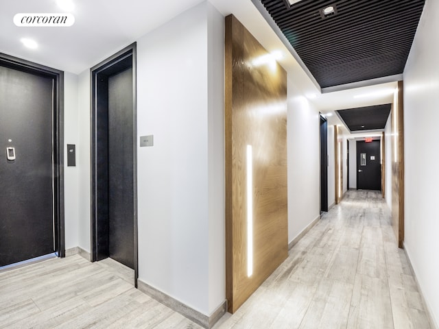 hallway with light hardwood / wood-style floors and elevator