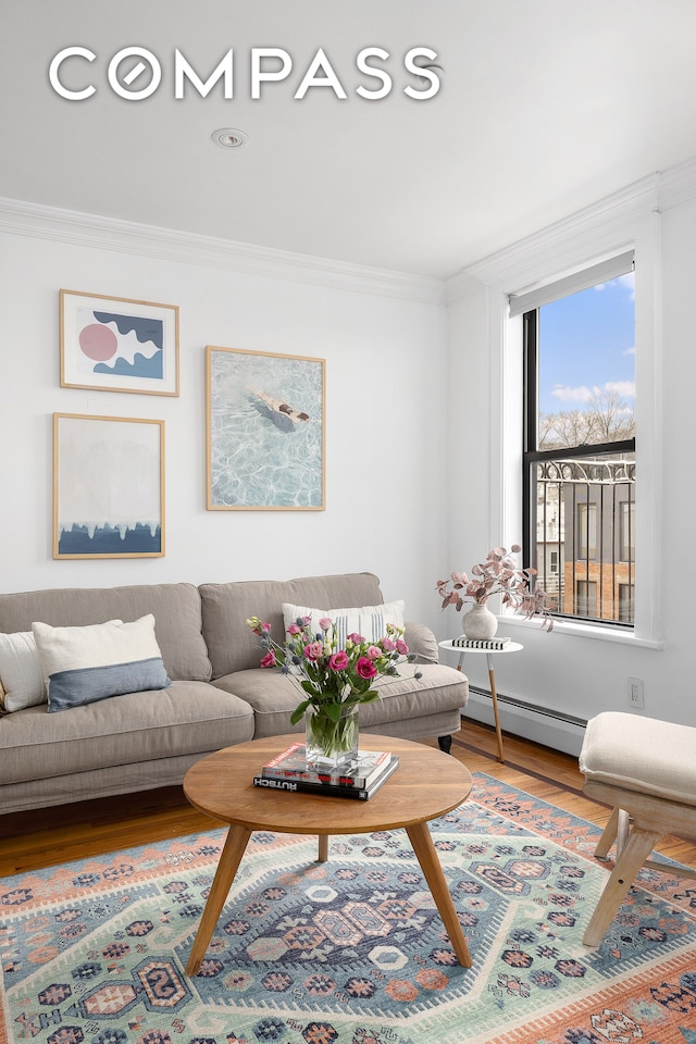 living room with ornamental molding, a baseboard heating unit, and wood-type flooring