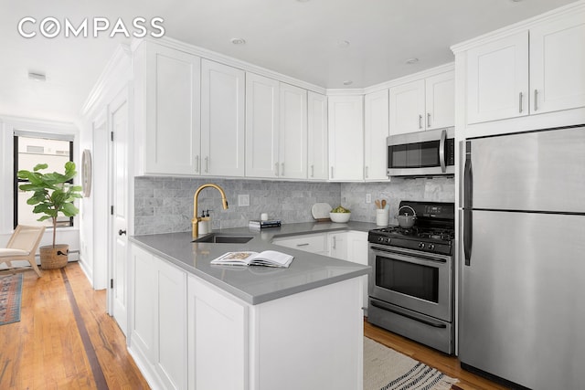 kitchen with appliances with stainless steel finishes, white cabinetry, and sink