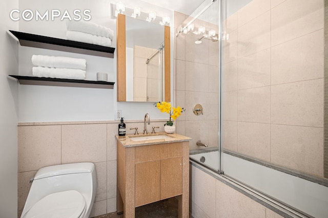 full bathroom with toilet, vanity, tile walls, and combined bath / shower with glass door