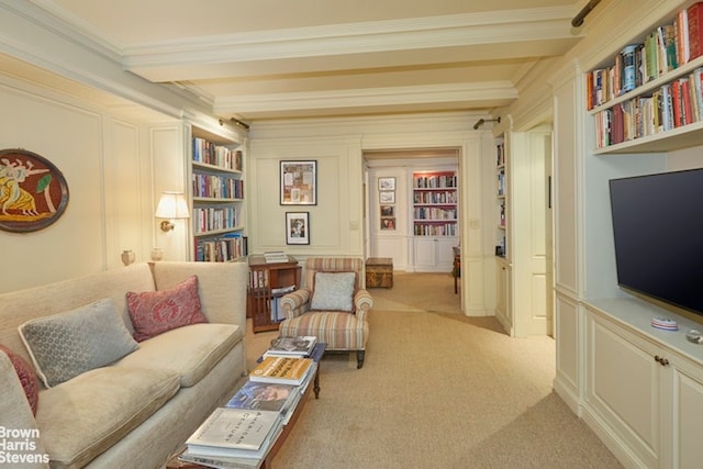 sitting room featuring built in shelves, light colored carpet, ornamental molding, and beam ceiling