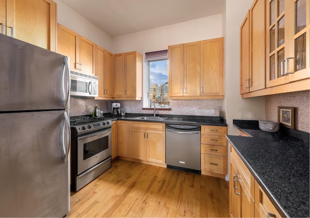 kitchen featuring decorative backsplash, stainless steel appliances, light hardwood / wood-style flooring, and sink