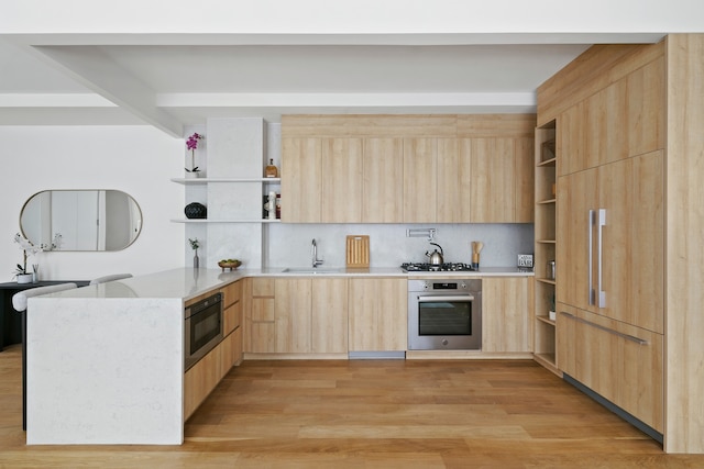 kitchen with tasteful backsplash, stainless steel appliances, sink, light brown cabinets, and light hardwood / wood-style flooring