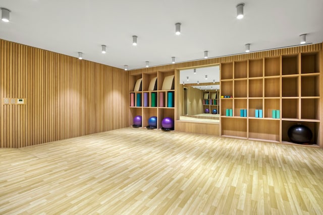 workout area with wood-type flooring and wooden walls