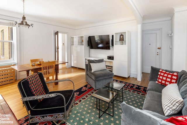 living room with a chandelier, light hardwood / wood-style flooring, and crown molding