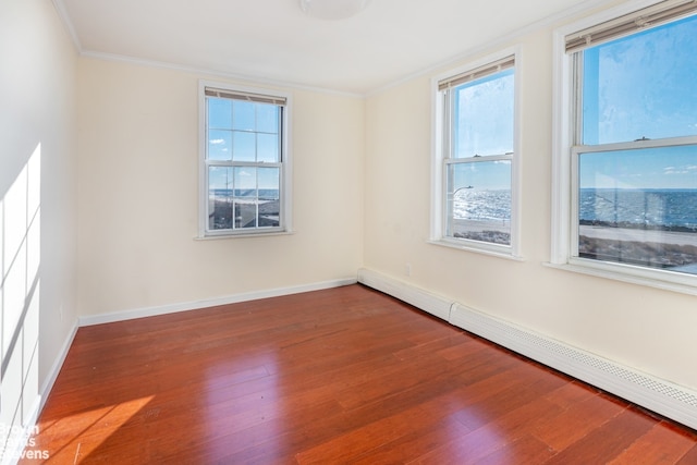 spare room with crown molding, wood-type flooring, and a baseboard heating unit