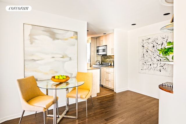 kitchen featuring dark hardwood / wood-style flooring, stainless steel appliances, light brown cabinetry, and tasteful backsplash