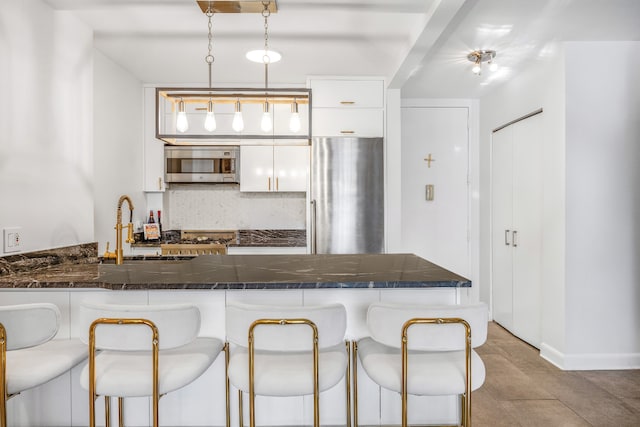 kitchen with sink, a breakfast bar area, decorative light fixtures, white cabinetry, and stainless steel appliances